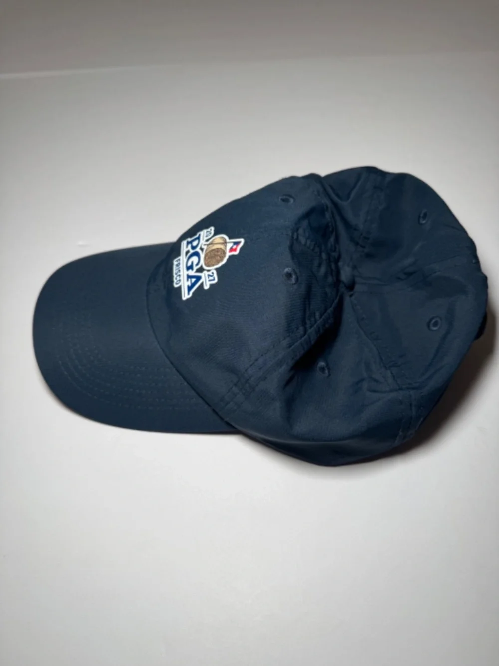 Description: Imperial golf cap in navy blue featuring an embroidered 2027 PGA Fr
